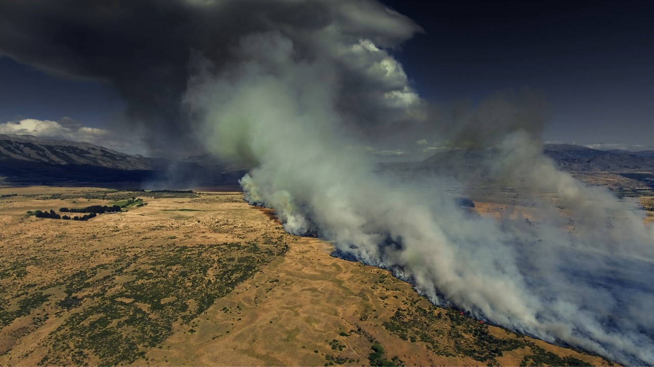 Aerial view of fields with large billows of smoke 