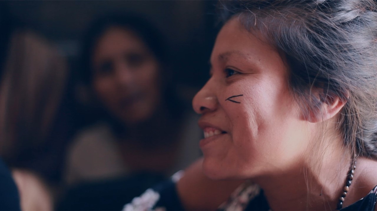 Closeup of a smiling woman with an arrow tatoo poi