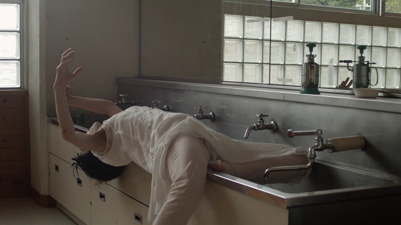 A woman lies on the edge of a school sink
