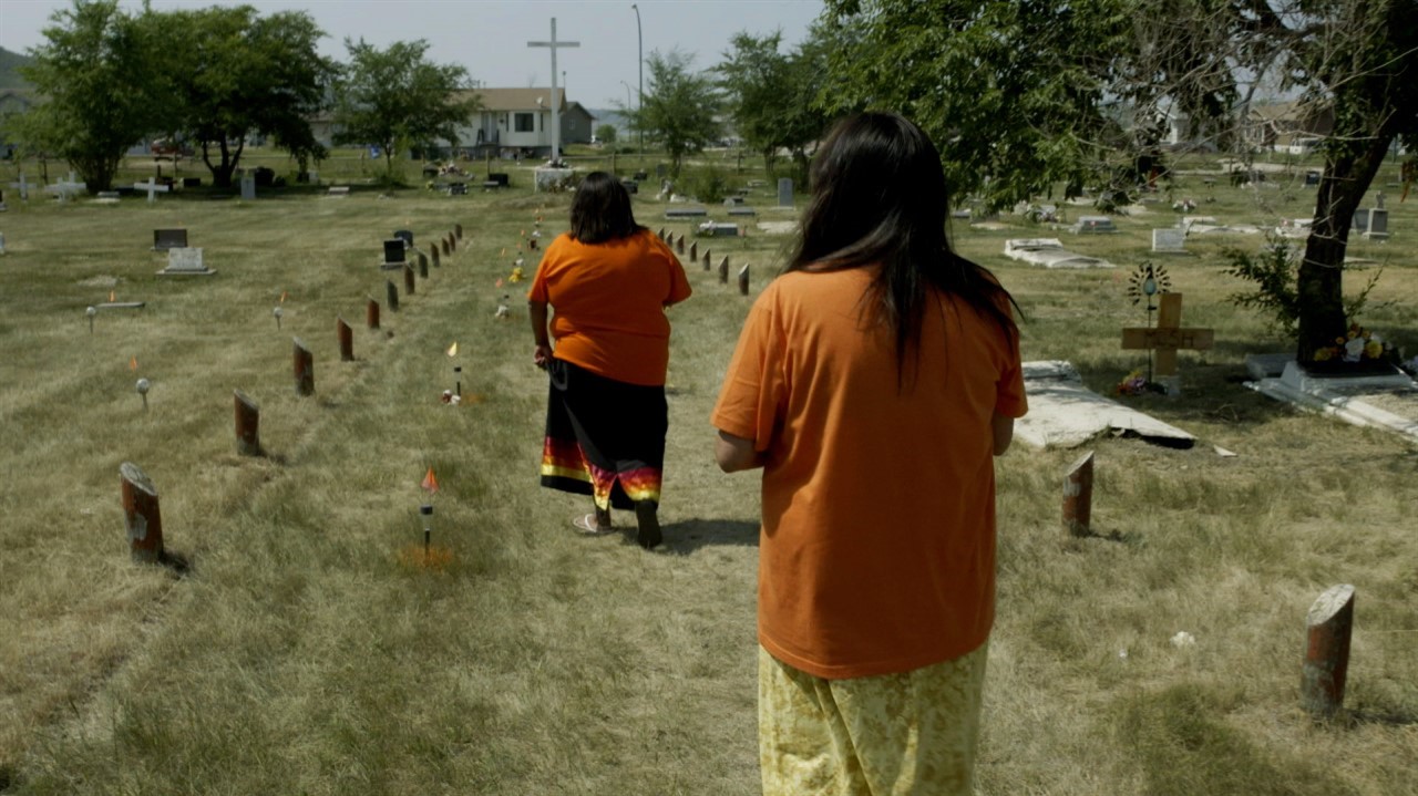 Women in orange shirts in graveyard