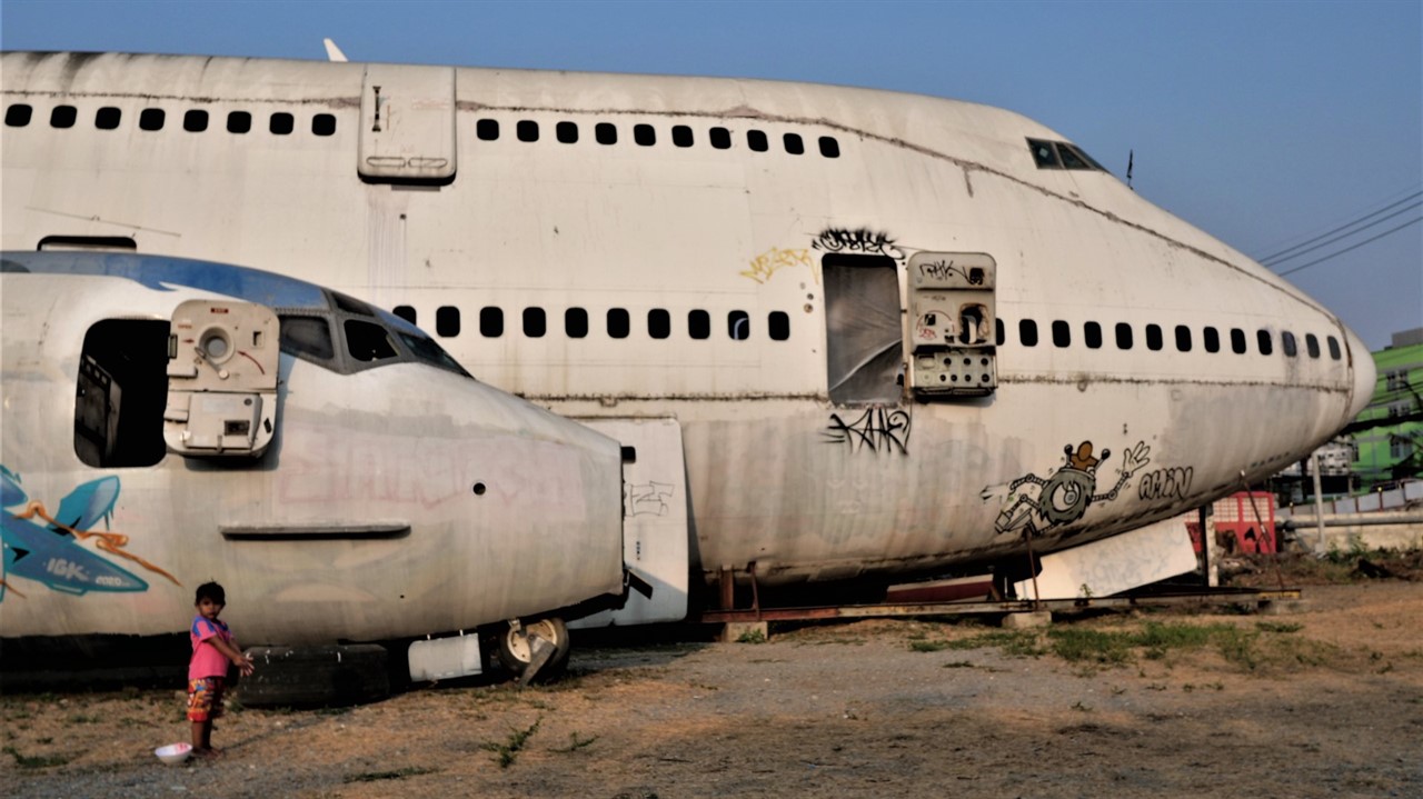 Small child standing next to two abandoned planes