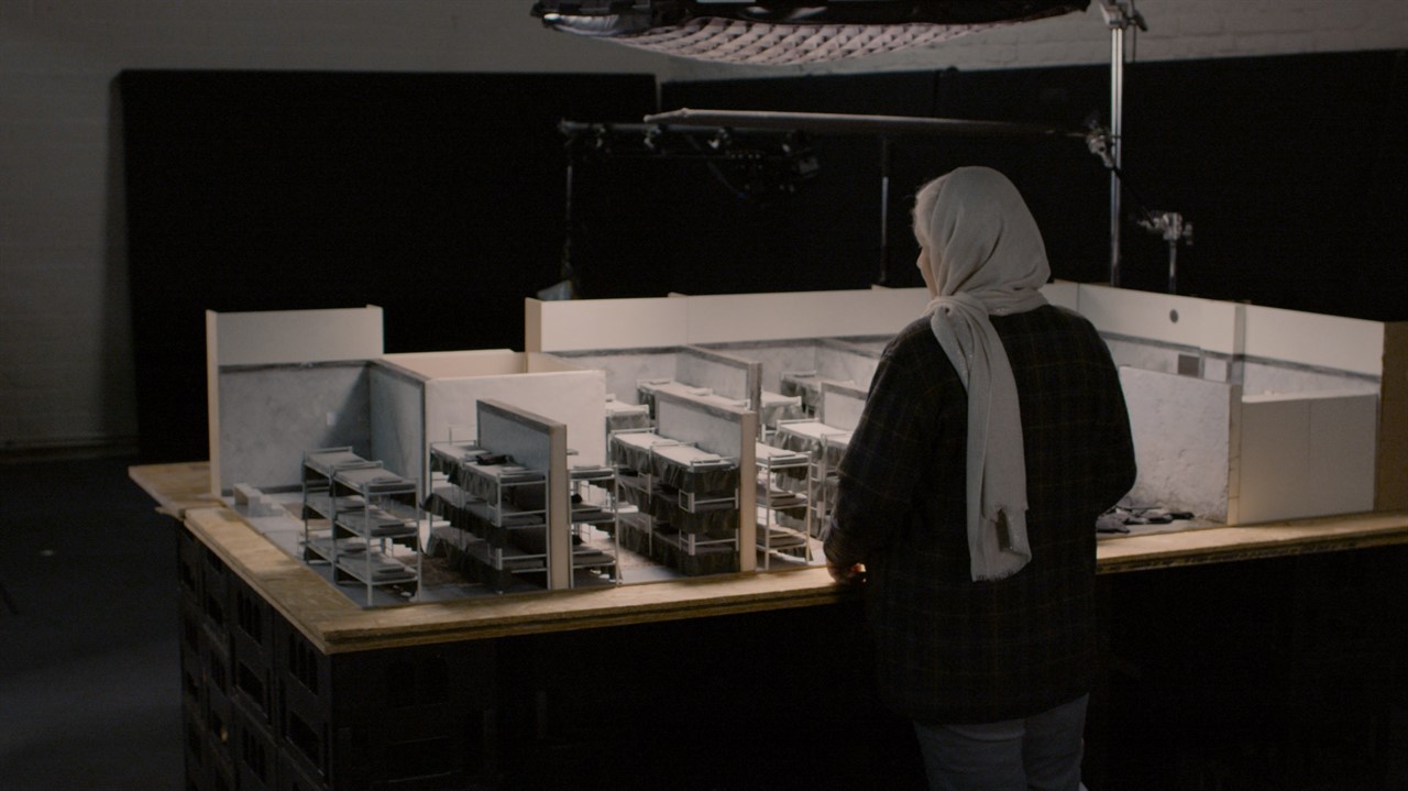 A woman in a hijab looks at a model of bunkbeds