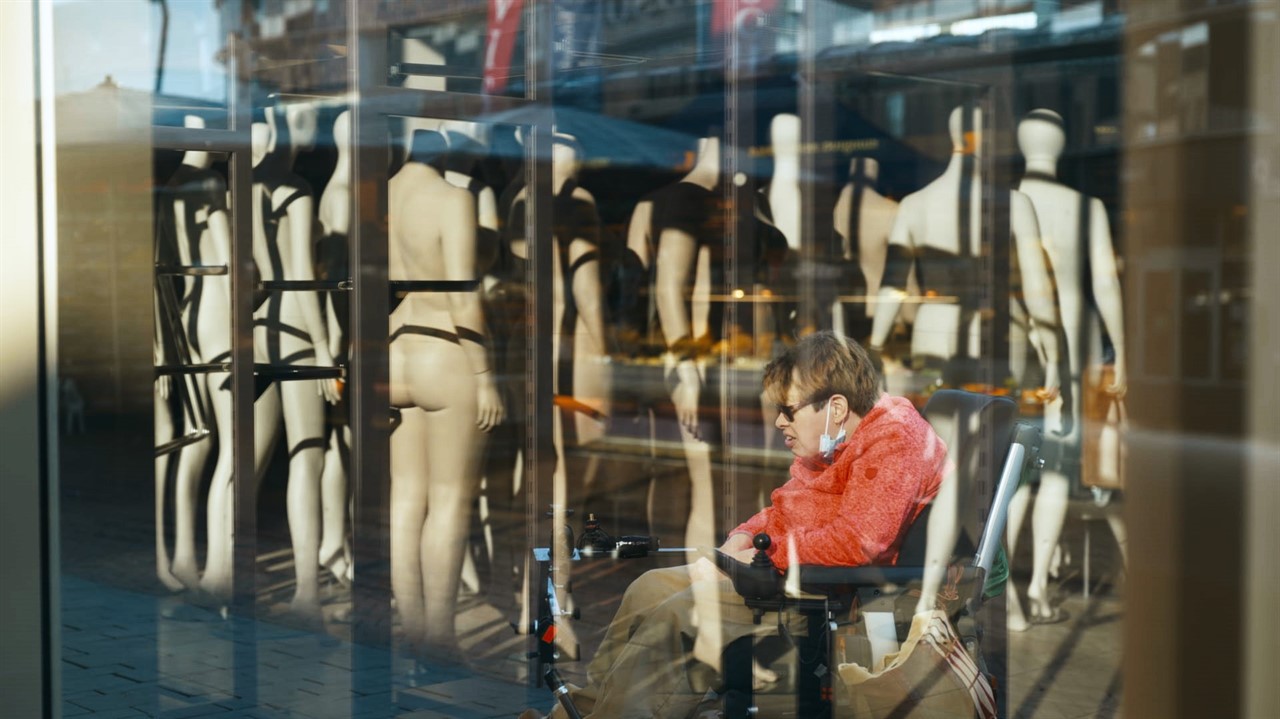 Woman in motorized chair, in front of mannequins