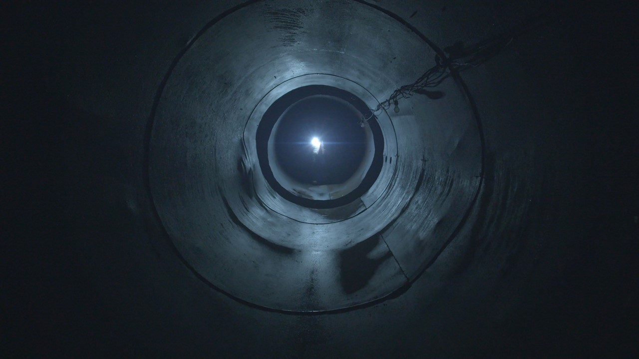 Person with a flashling looking inside a tunnel