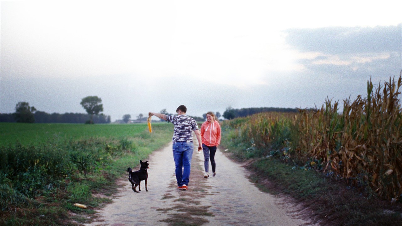 Two women and a dog walk along a rural road
