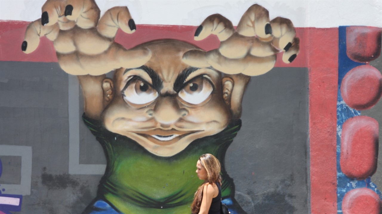 Woman walks by mural on wall