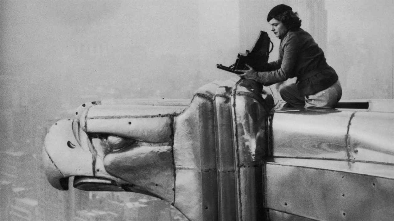 Woman sits on large bird sculpture with camera