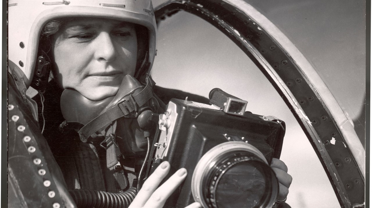 Woman in a flight helment looks through a camera