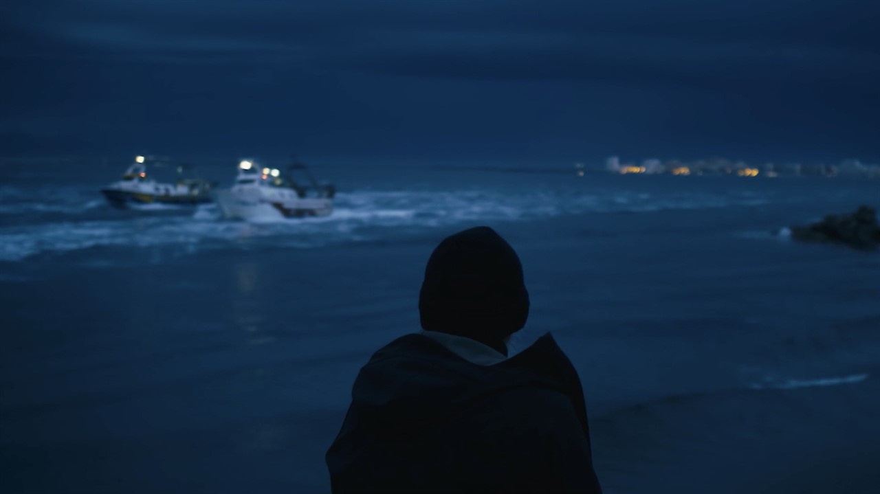 Person in silhoette watching boats at night
