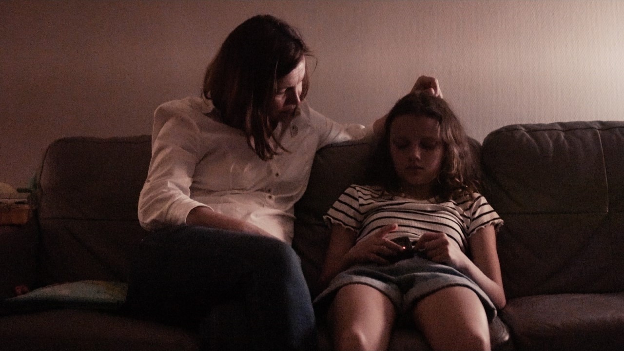 A woman and girl sit on a couch