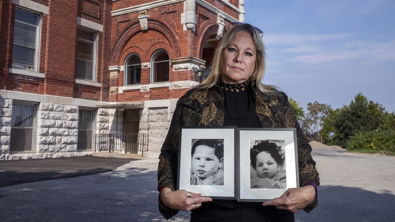 Woman holding two photos of children