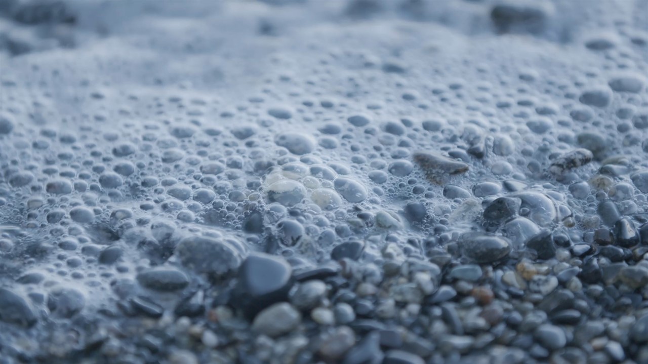 Closeup of bubbly waters edge and stone beach