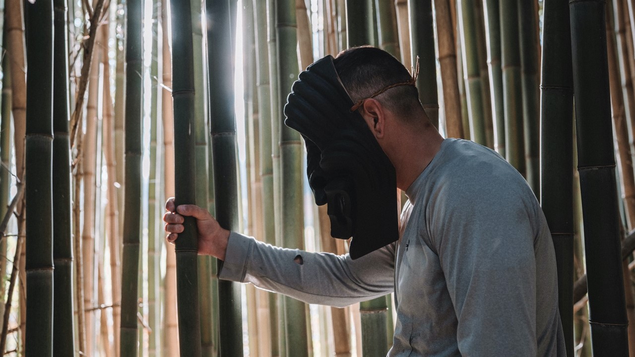 Man in large mask in a bamboo grove
