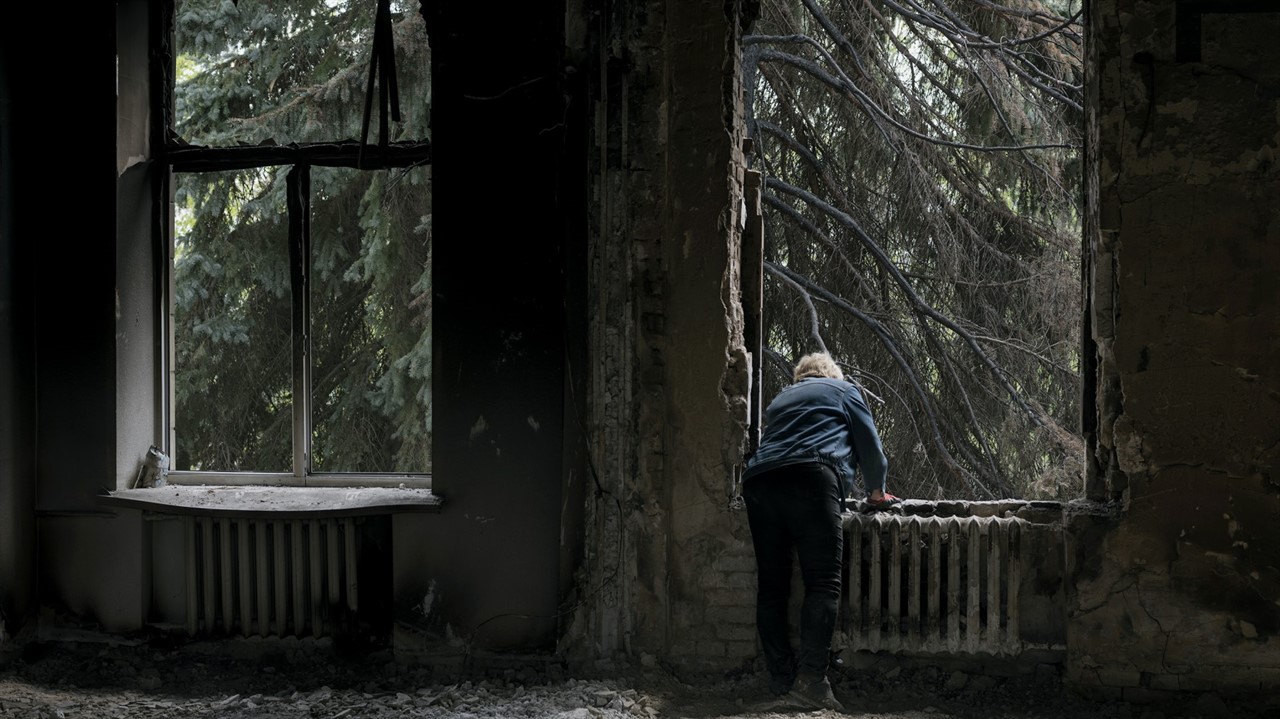 A person looks out the window of a derelict buildi