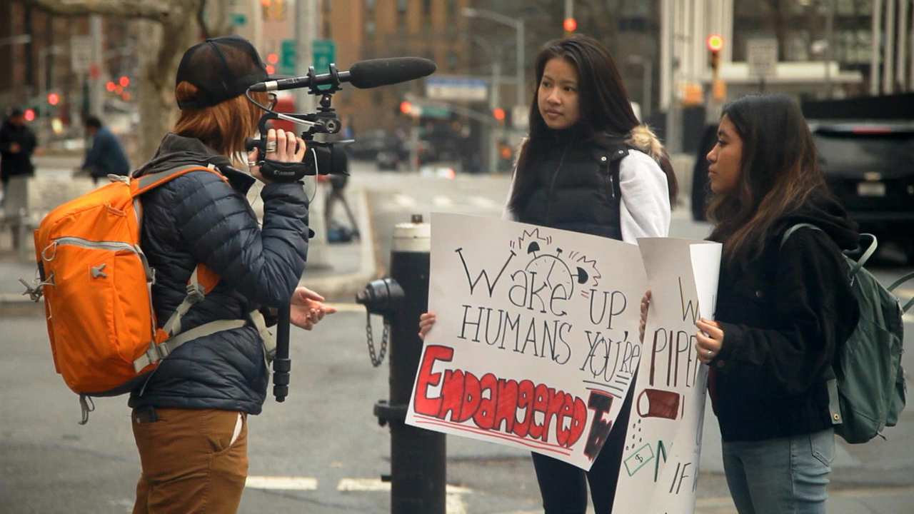 a person filming two people with signs